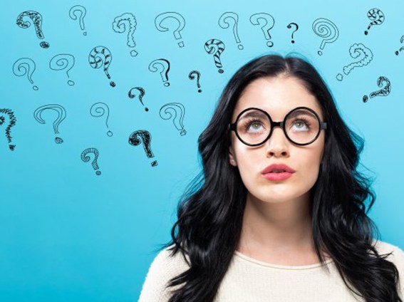 Young woman looking upwards at the question marks floating over her head